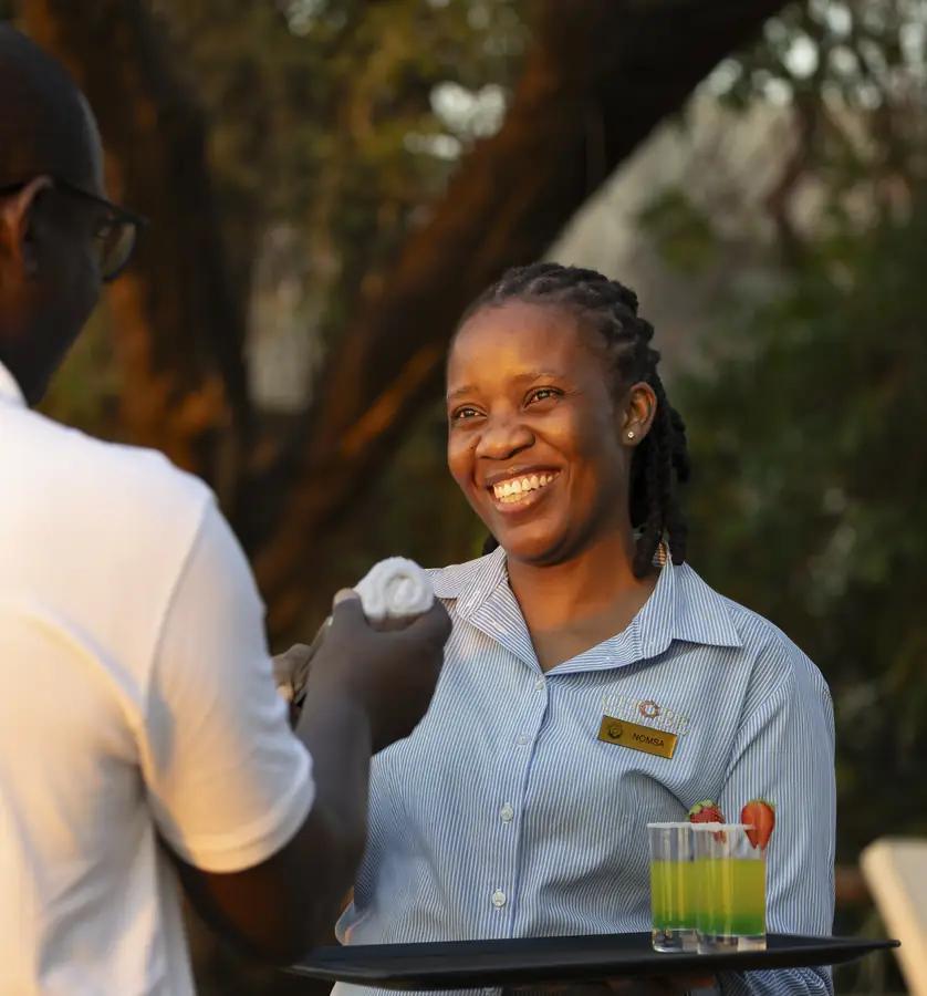 A smiling host handing a guest a welcome drink